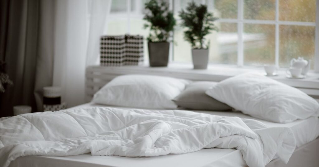 Empty bed with a crumpled-up wool duvet.