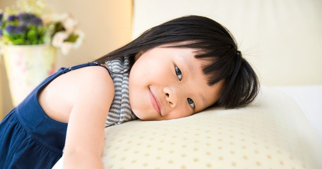 Young girl resting her head on a latex pillow.