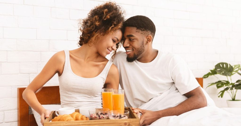 Couple enjoying a romantic breakfast in their organic latex bed. 