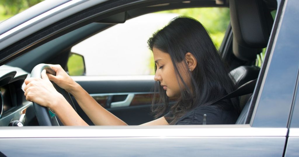 Sleep deprived woman behind the wheel of her car.