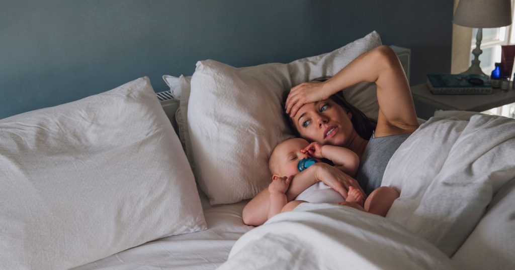 Mom suffering from sleep deprivation laying awake next to her baby.