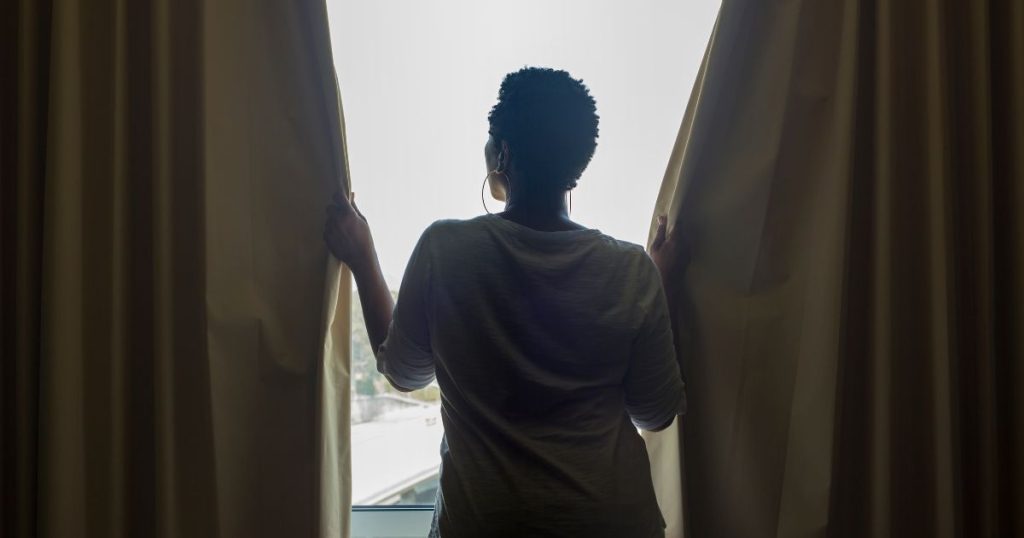 Woman closing the curtains in a guest house.