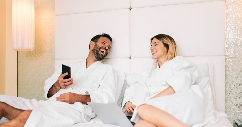 Couple laughing in bed at a guest house.