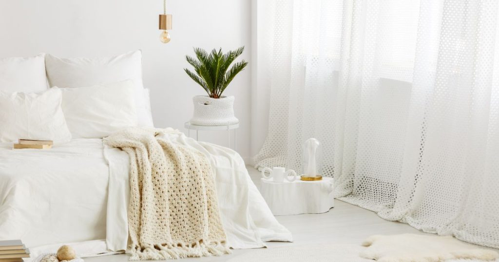 Bedroom with white and cream bedding draped over a latex mattress