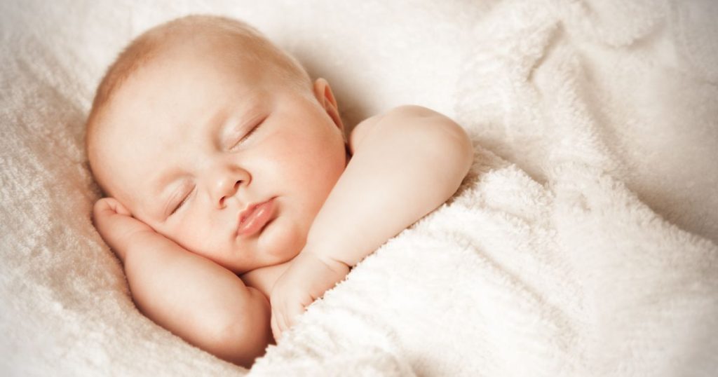 Baby sleeping under a wooden duvet.