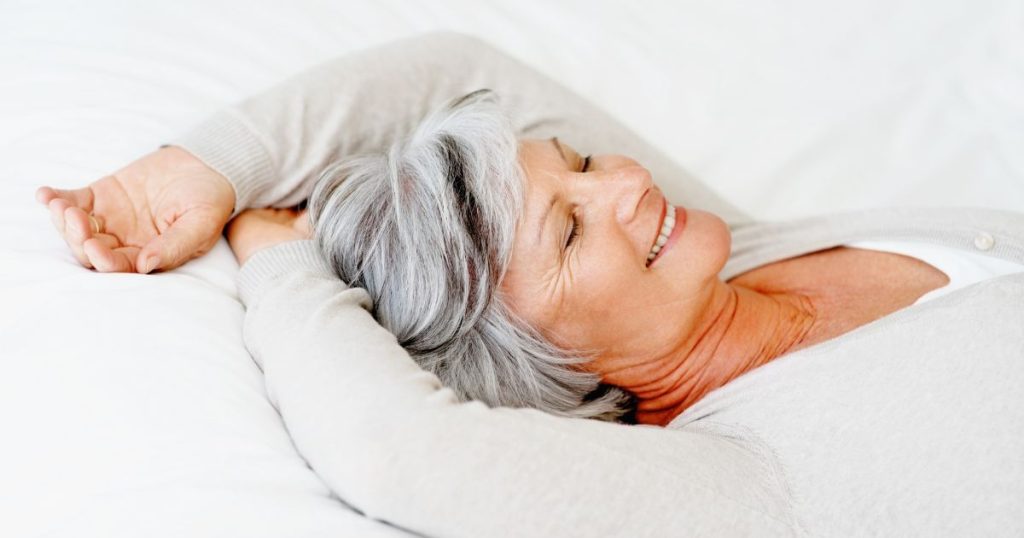 Senior woman smiling in bed as she relaxes.