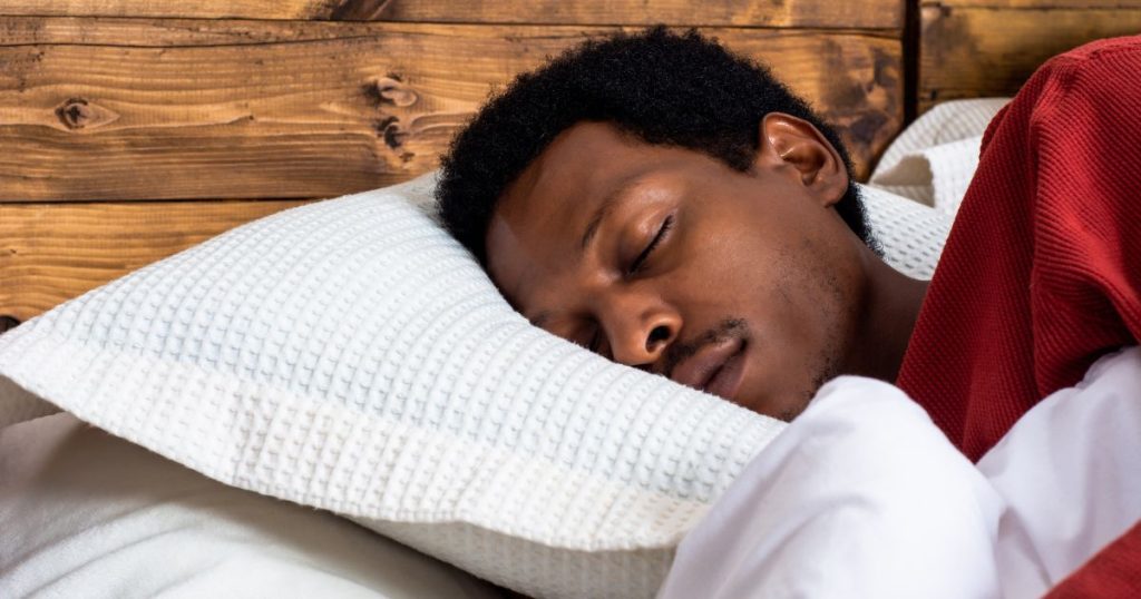 Man sleeping comfortably on his side on a mattress that is designed for back pain relief.
