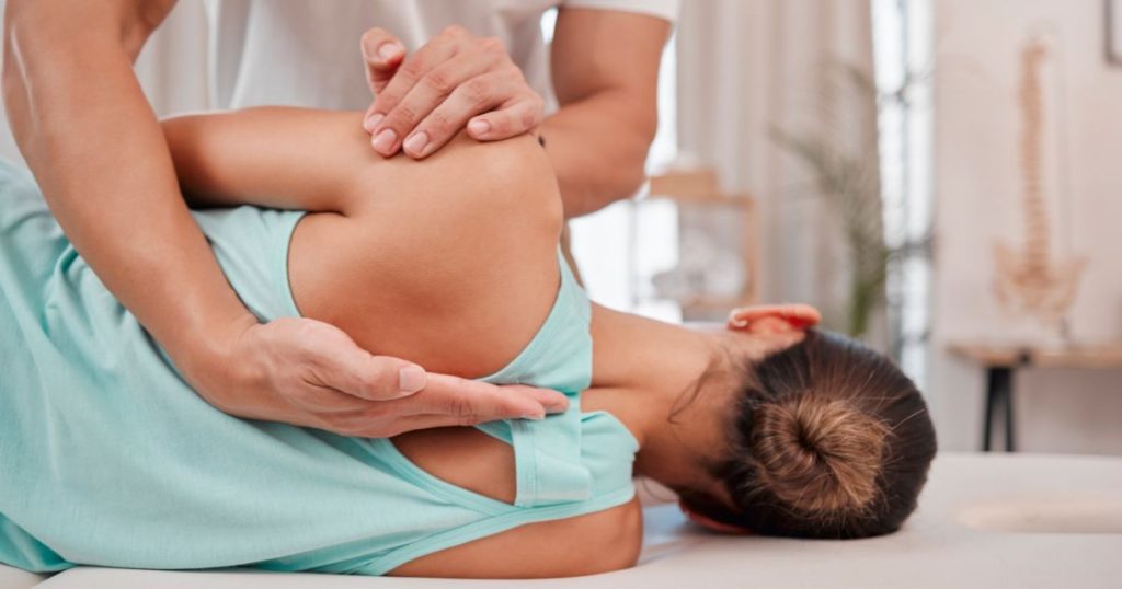 Physiotherapist helping patient achieve neutral spine alignment on a mattress.