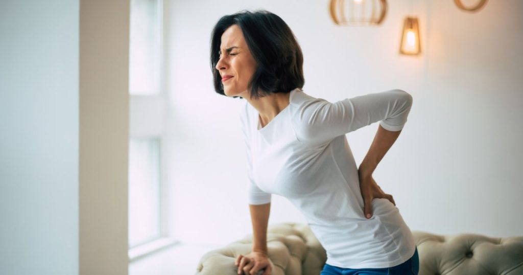 Woman experiencing lower back pain after sleeping on a soft mattress.