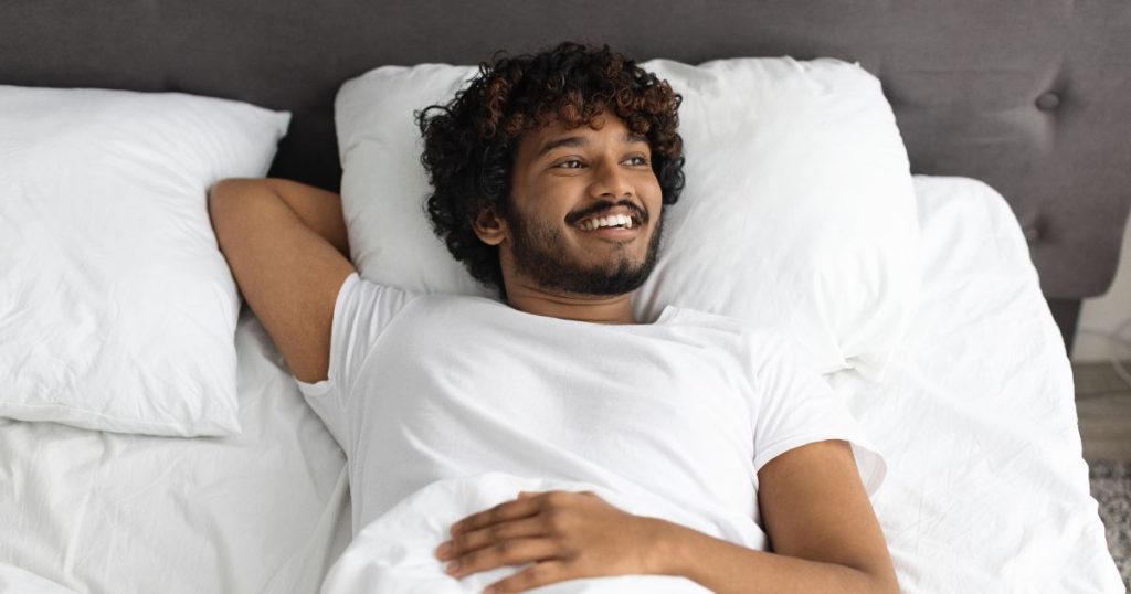 Man relaxing on his back in bed