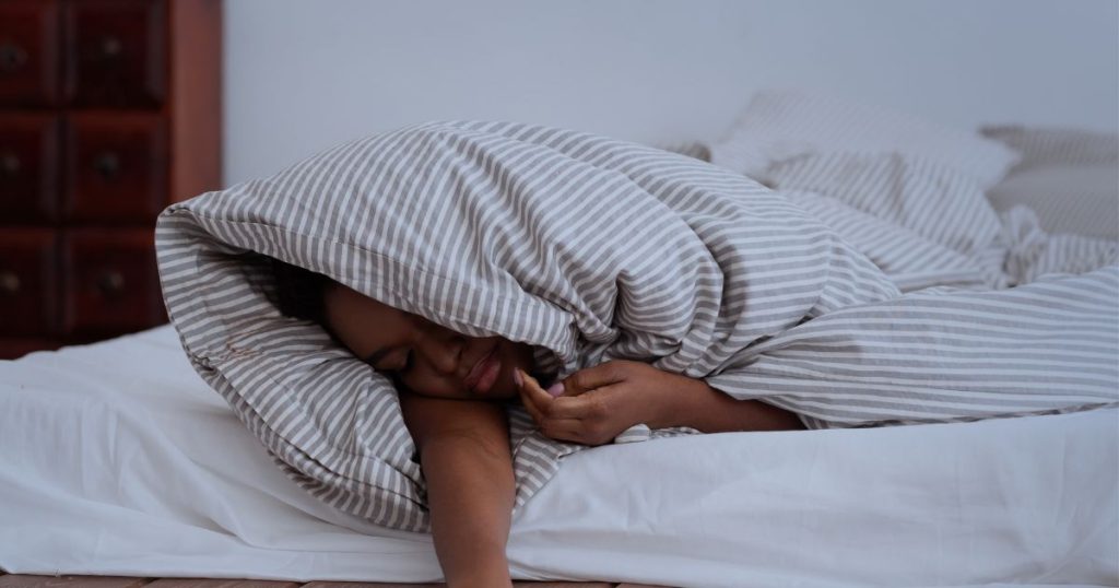 Woman trying to sleep while rolling to the middle of the bed.