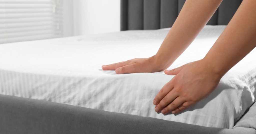 Hands touching a mattress to determine if it's too soft
