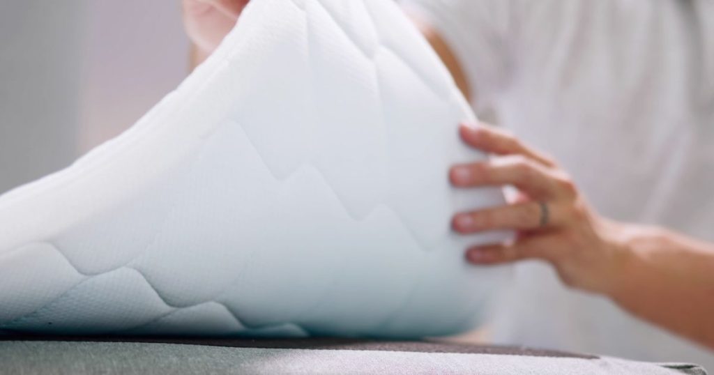 Person bending a mattress topper