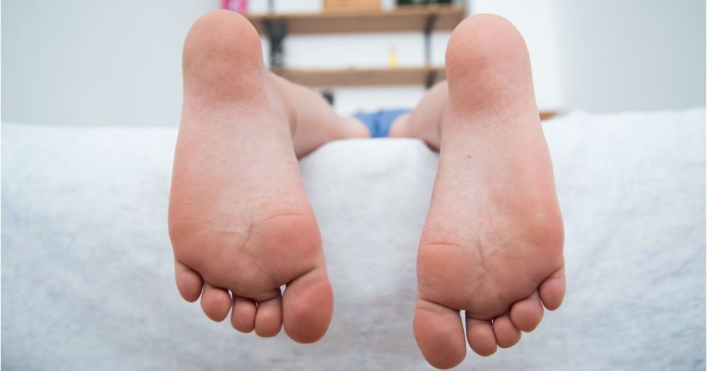 A tall person's feet hanging off the edge of a normal bed