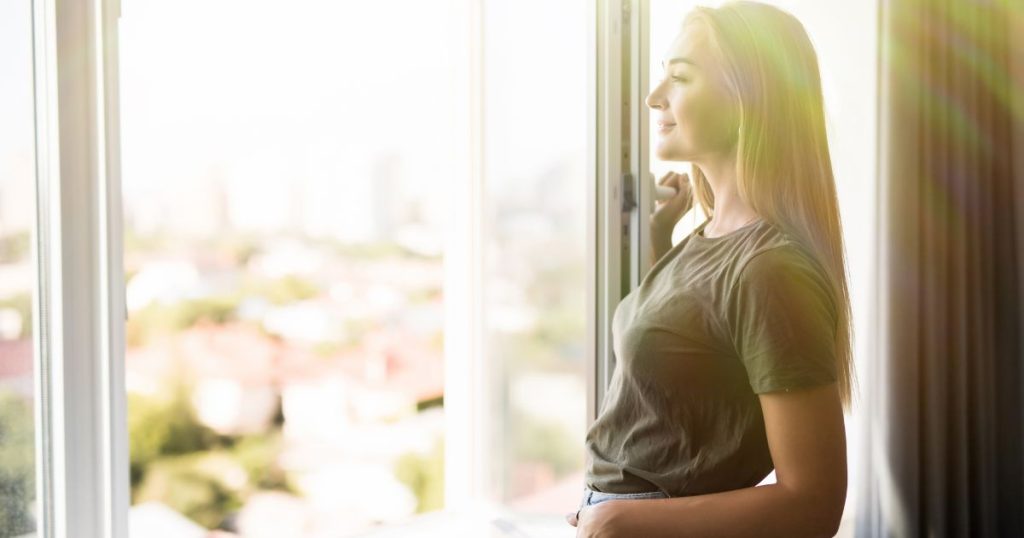 Woman standing by an open bedroom window